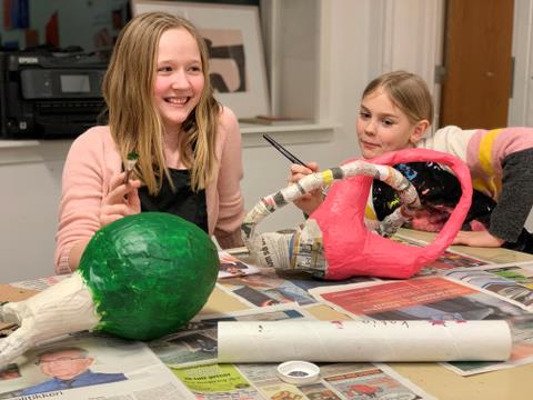 På billedet er der to børn der er kreative med at beklæde to figurer med papmache 